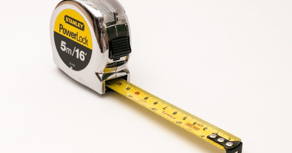 Property Measurements Guide: How to Measure a Plot Accurately | UA Map Studio Seohara, Dist- Bijnor | A close-up photograph of a Stanley PowerLock 5m/16ft measuring tape on a white background.