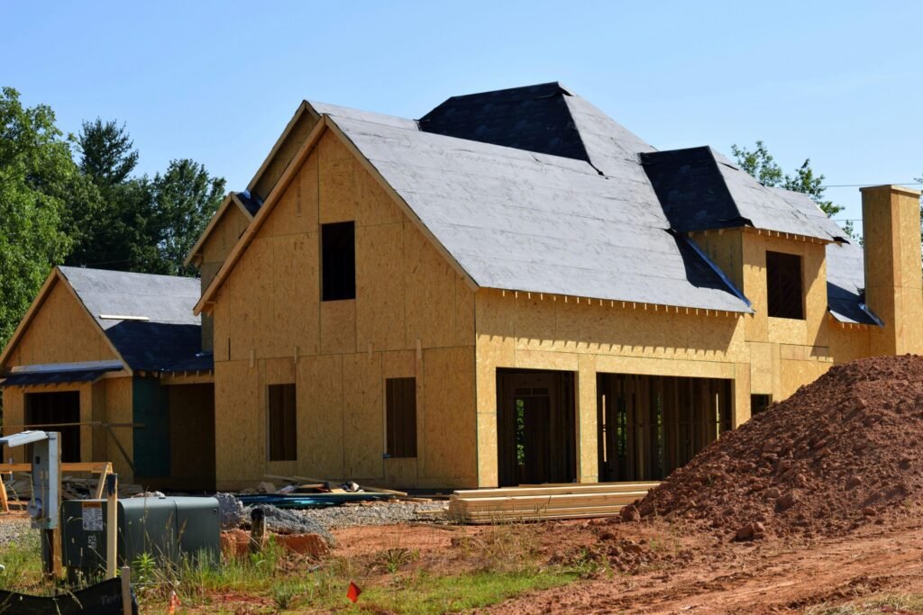 Mistakes to Avoid While Building a House: Planning mistakes, Budget issues & Contractor problems | UA Map Studio | Civil Engineer & Property Consultant in Seohara, District- Bijnor | | A partially built wooden house under construction, showcasing its progress and design in daylight.