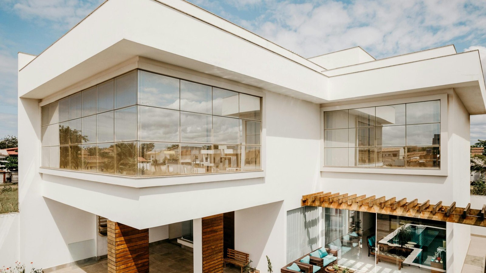 Exterior of contemporary cottage with large windows and stylish terrace against cloudy blue sky