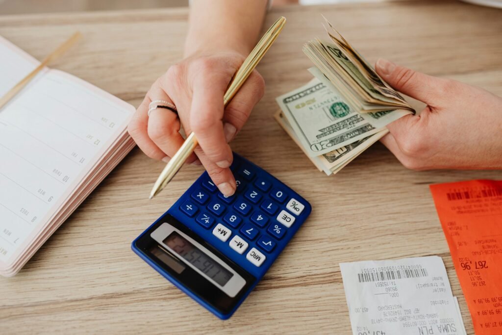 Mistakes to Avoid While Building a House | Inadequate Financial Planning | Hands handling cash and calculator for budget planning. Modern financial scene.