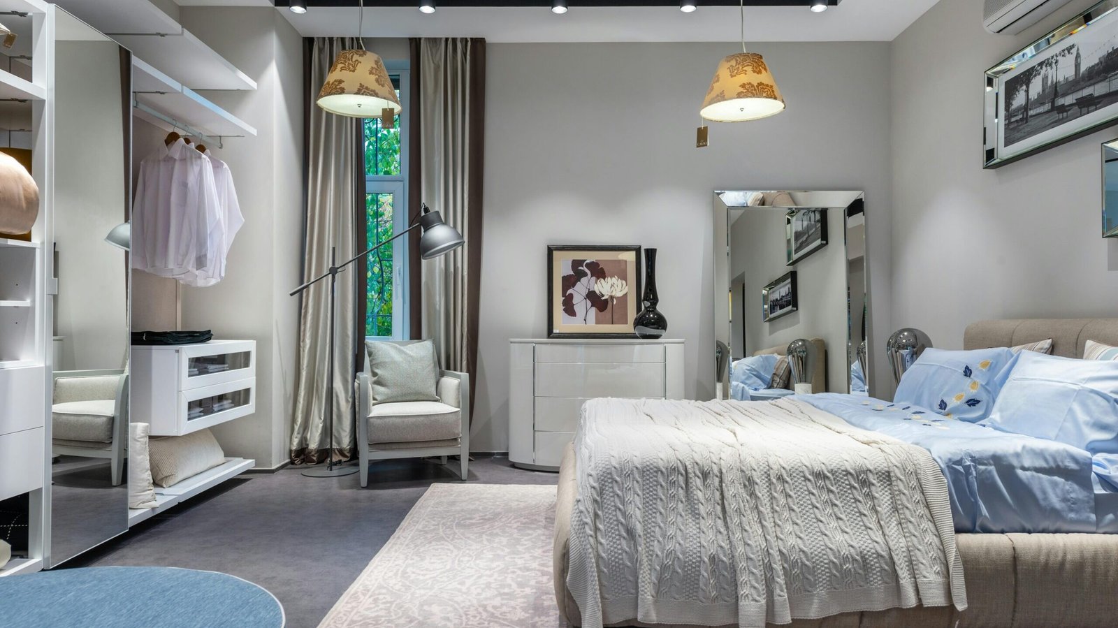 Comfortable bedroom with knitted coverlet and cushions built in spacious wardrobe armchair chest and mirror and hanging lamps