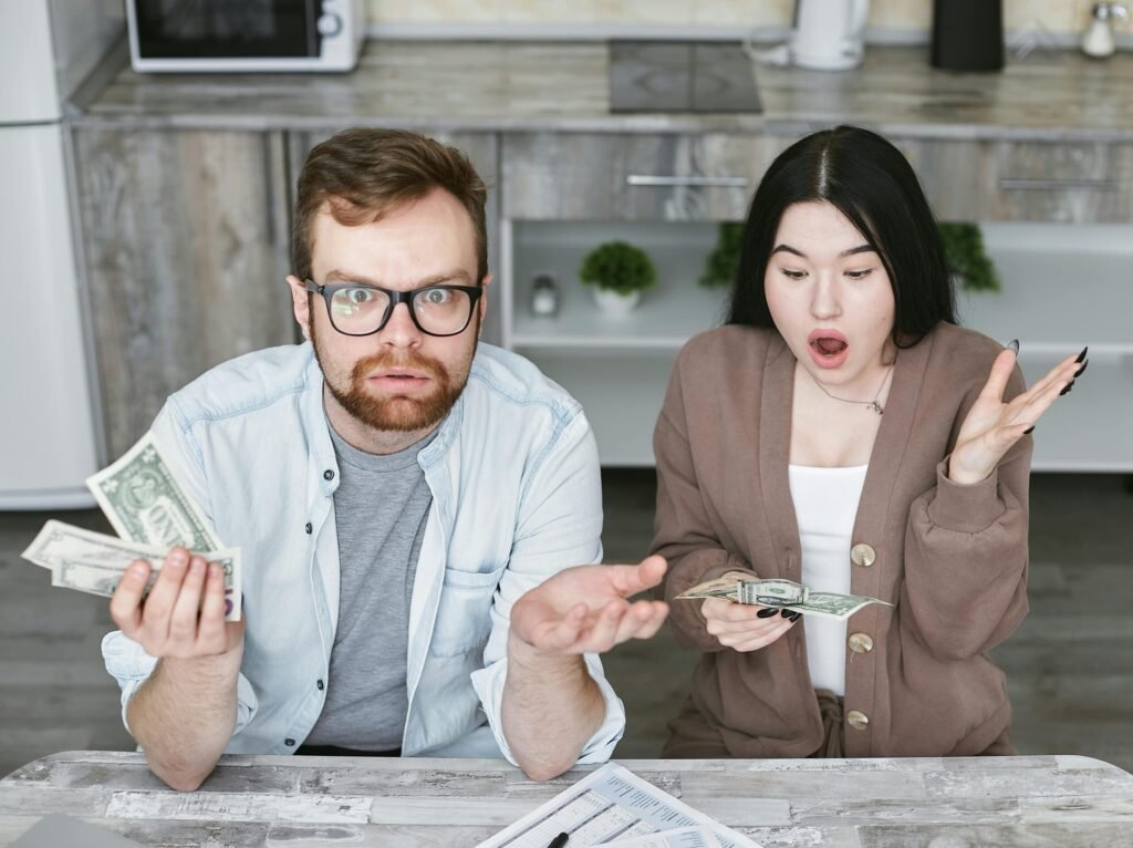 Mistakes to Avoid While Building a House | Interracial couple shocked while handling cash in a modern kitchen. Captivating expressions indoors.