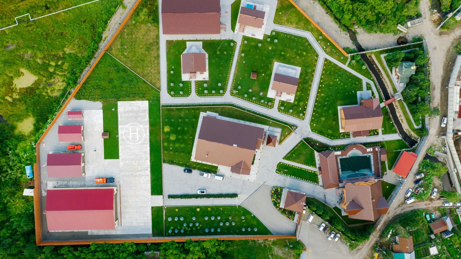 घर का नक्शा बनवाते समय क्या ध्यान रखें: UA Map Studio Seohara | Dist- Bijnor | Aerial view of modern residential area with helipad, surrounded by greenery.