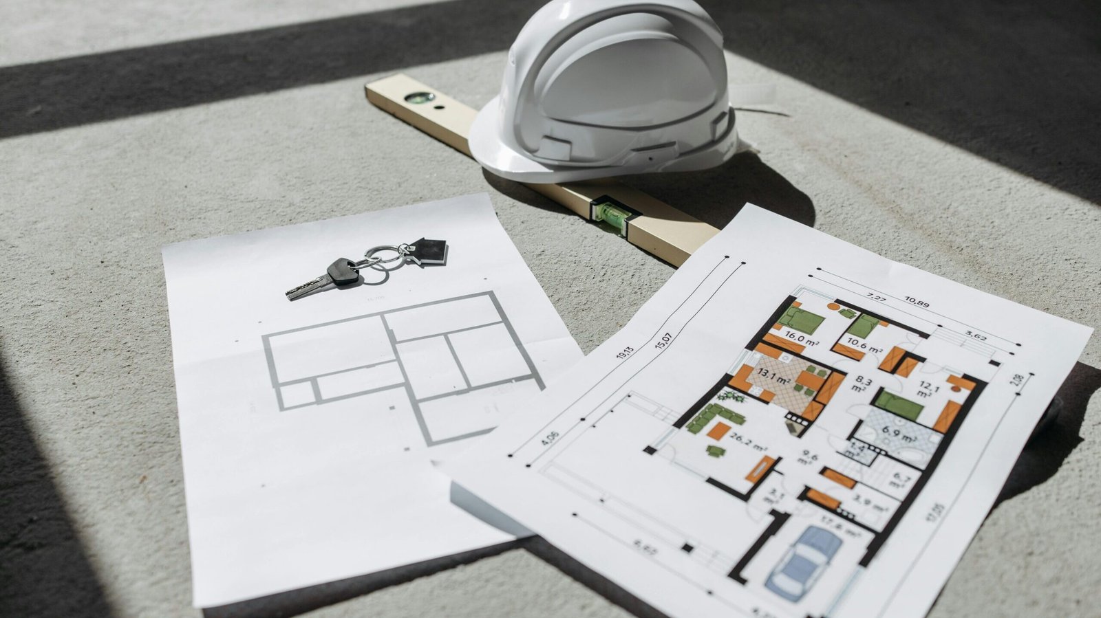 Key Projects Undertaken by UA Map Studio | Architectural floor plans with helmet and keys on sunlit floor, perfect for real estate or construction themes.